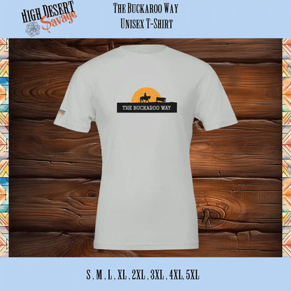 The Buckaroo Way unisex tee captures the spirit of the American West with a striking silhouette of a buckaroo herding cattle on horseback, set against the backdrop of a radiant sun on a silver Bella T-Shirt